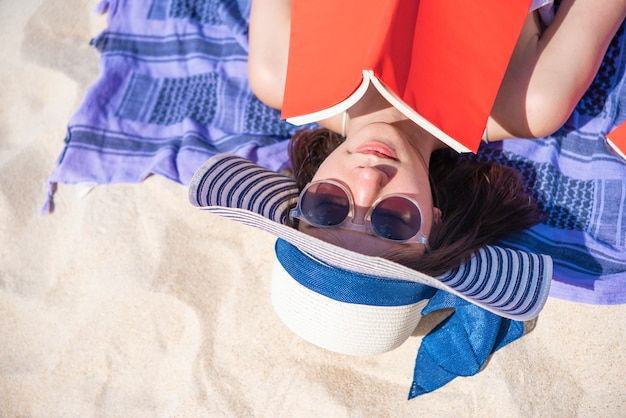 Close-up van het mooie vrouw liggen en het lezen van een boek op het tropische strand in de zomertijd.