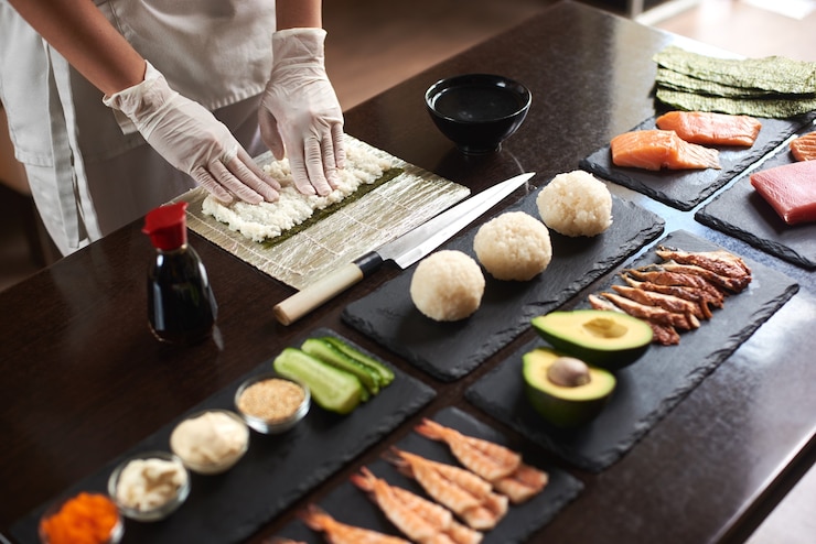 Foto close-up van het proces van het bereiden van rollende sushi. nori en witte rijst. de handen van de chef raken rijst aan. chef begint sushi te koken