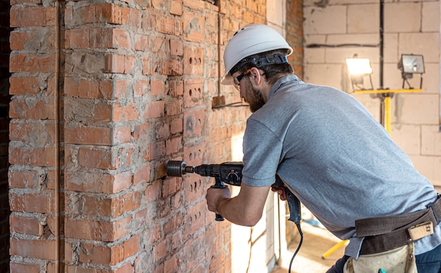 Close-up van het proces van het boren van een bakstenen muur op een bouwplaats