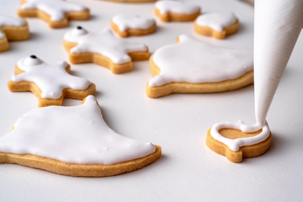 Close-up van het versieren van schattige Halloween-koekjes met glazuur in glazuurzak