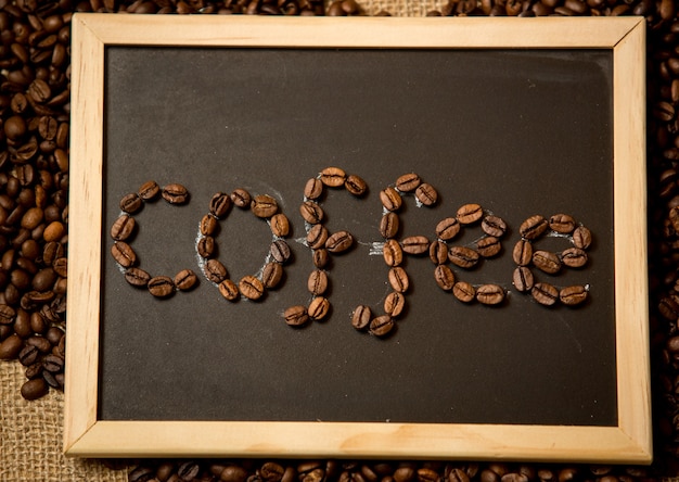 Close-up van het woord "koffie" geschreven door koffiebonen op zwart krijtbord