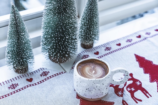 Close-up van hete koffie latte met latte art melkschuim in bekermok met kerstdecors en kerstballen op houten bureau Vrolijk kerstfeest en nieuwjaar vieren