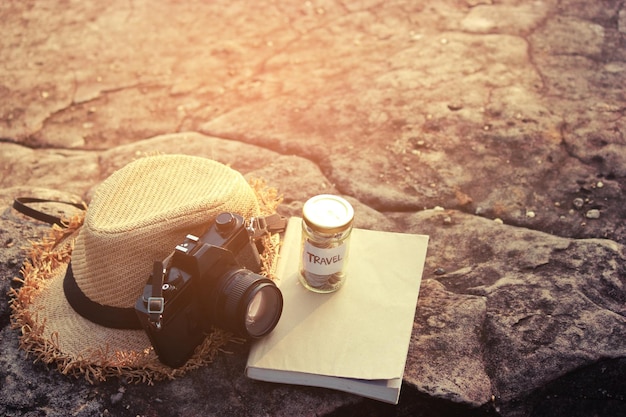 Foto close-up van hoed en camera door boek op rots