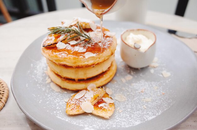 Foto close-up van honing die op een pannenkoek op een bord wordt gegoten