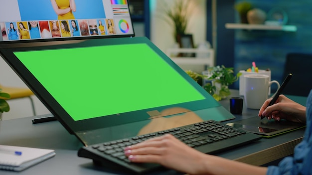Close up van horizontaal groen scherm op computer met retoucheer-app. fotograaf die foto's bewerkt met grafisch tablet terwijl hij chroma key heeft met mockup-sjabloon en geïsoleerde achtergrond