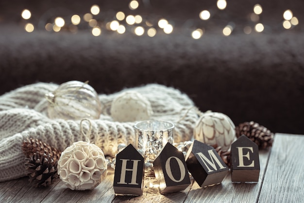 Close up van houten letters maken het woord thuis, details van kerstdecor op onscherpe achtergrond met bokeh.