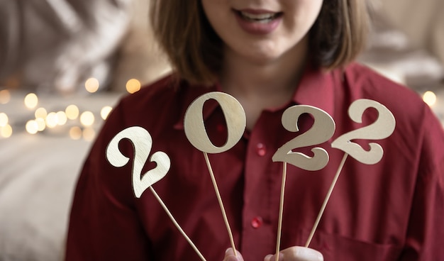 Foto close-up van houten nummers 2022 op stokken in de handen van een meisje, op een onscherpe achtergrond.