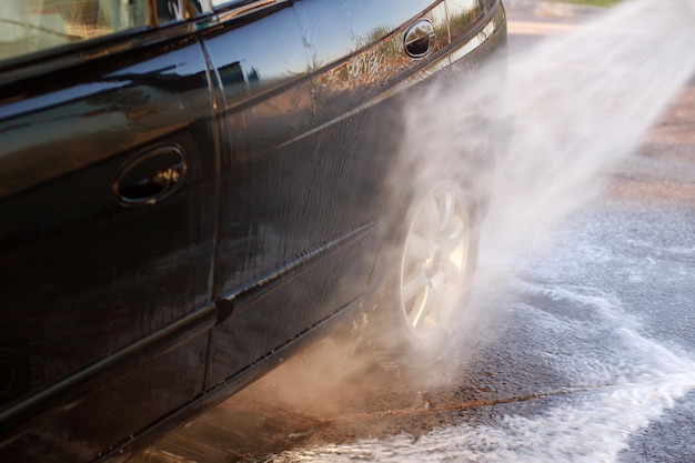 Close-up van iemand die een auto wast in een wasstraat met een hogedrukspuit