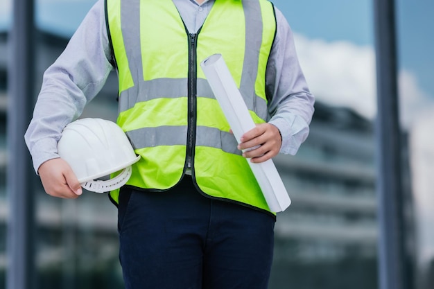 Close up van ingenieur jonge man dragen veiligheidsvest en helm houden op bouw bouwplaats achtergrond engineering bouwvakker concept