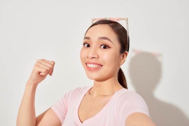 Close-up van jonge Aziatische mooie vrouw die lacht en selfie neemt op witte achtergrond