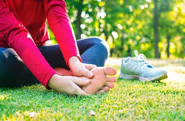 Close-up van jonge Aziatische sportvrouw heeft pijn aan spieren en gewrichten tijdens buitenoefeningen, over trainning of hardlopen en sportwerving concept