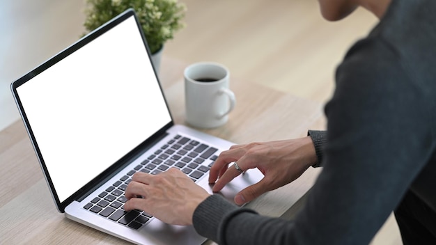 Close-up van jonge man freelancer met behulp van laptopcomputer thuis surfen op internet.