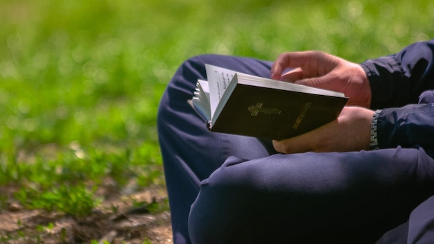 Close up van jonge man met een bijbel in zijn handen zittend in park mensen kennis onderwijs en re
