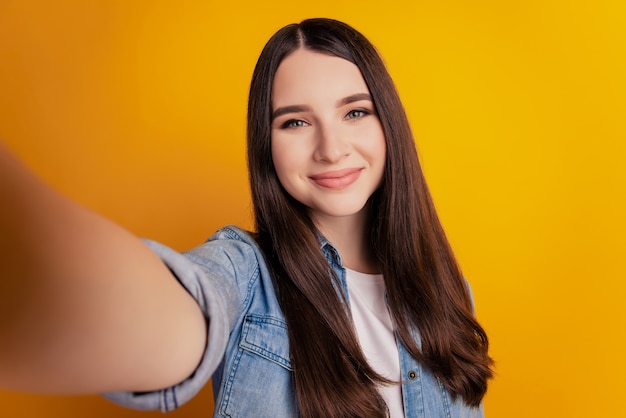 Close-up van jonge mooie vrouw die selfie op gele muur neemt