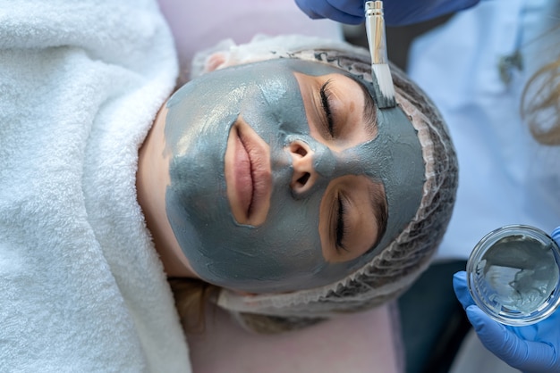Close-up van jonge vrouw die hydraterende procedure gezichtsmassage krijgt door dermatoloog in schoonheidskliniek. Huidverzorgingsconcept