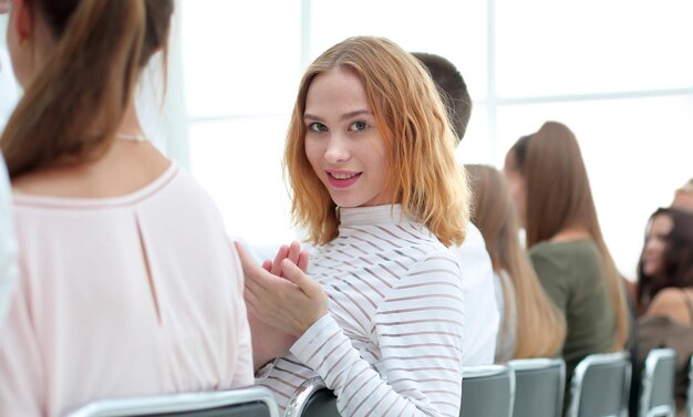 Close-up van jonge vrouw die op een rij zit met haar medewerkers