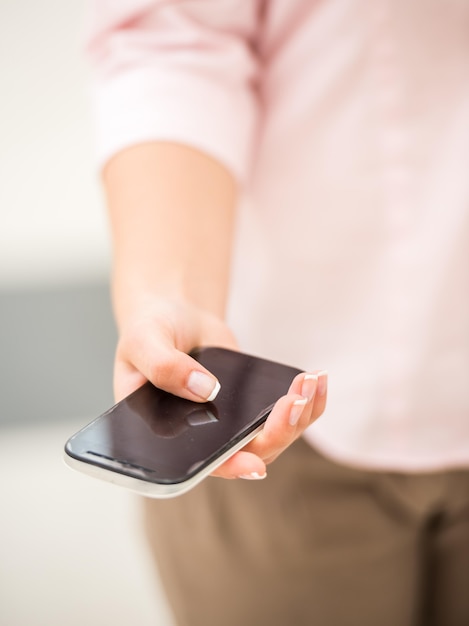 Close-up van jonge vrouw die slimme telefoon houdt.