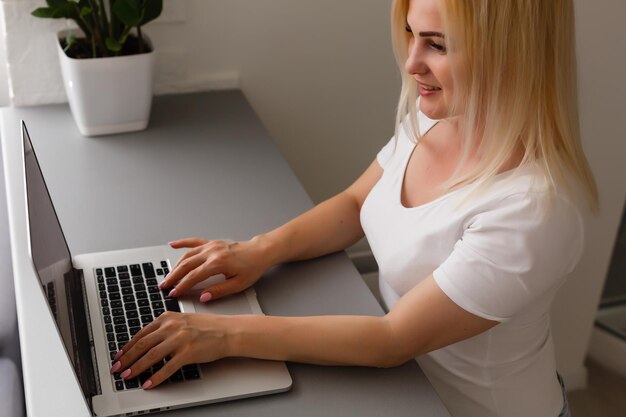 Close-up van jonge vrouw die thuis online laptop gebruikt