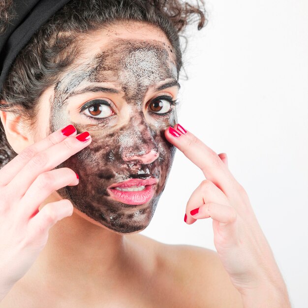 Close-up van jonge vrouw die zwart gezichtsmasker met haar vingers toepast