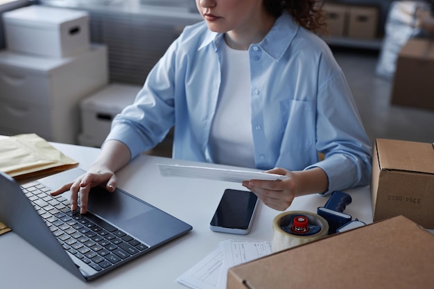 Close-up van jonge vrouw in vrijetijdskleding drukknop op laptop toetsenbord