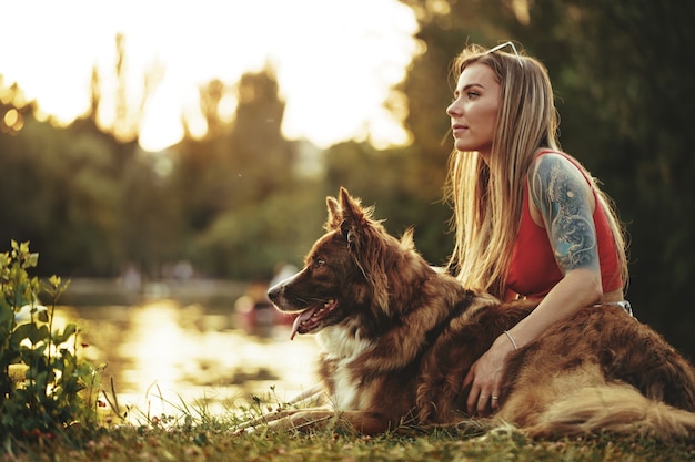 Close up van jonge vrouw met haar hond zittend op het gras in park