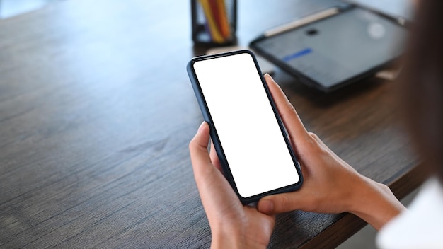 Close-up van jonge vrouw ontspannen op haar werkplek en het gebruik van mobiele telefoon.