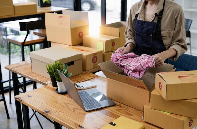 Close-up van jonge zakenman eigenaar kleding inpakken in kartonnen doos Jonge eigenaar vrouw opstarten voor Business Online mensen met online winkelen MKB ondernemer of freelance werkconcept