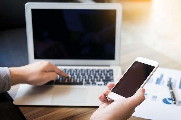 Close-up van jonge zakenman met behulp van mobiele smartphone voor het werken in zijn kantoor.