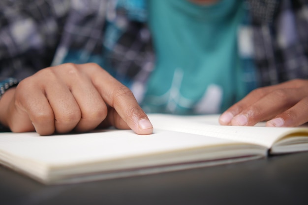 Close up van jongenshand die een boek leest