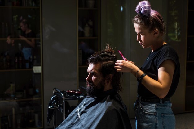 Close-up van kapper die baard aan man in kapperszaak stileert Persoonlijke stylist kapper