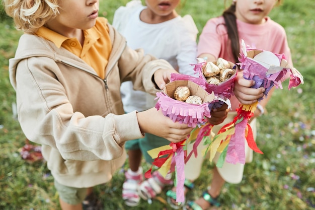 Close-up van kinderen die snoepjes van piñata vasthouden tijdens verjaardagsfeestje buitenshuis kopiëren ruimte