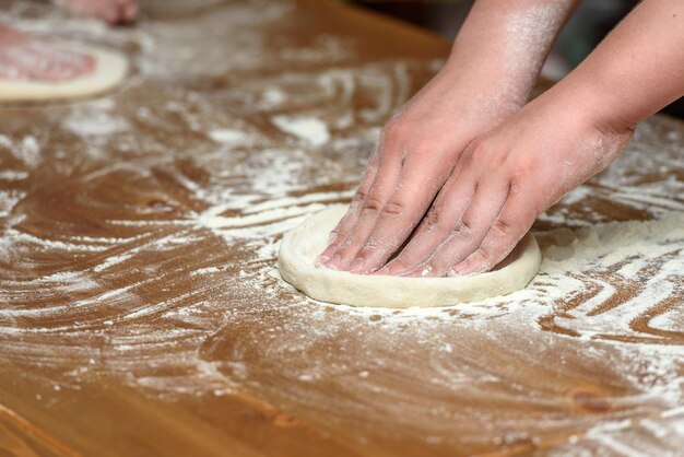 Close-up van kinderhanden die deeg voorbereiden op pizza