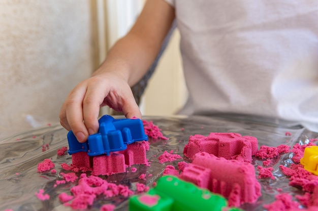 Close-up van kinderhanden die in kinetisch zand spelen