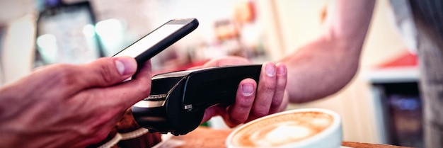 Close-up van klant met mobiele telefoon en barista met kaartlezer