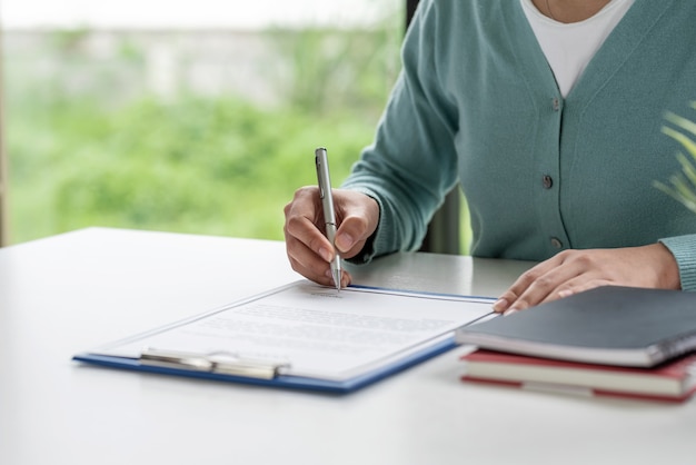 Close-up van klant ondertekent het contract een overeenkomst om een huis te verkopen met een agent op kantoor.