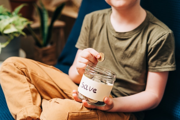 Close up van kleine kind jongen jongen handen grijpen en stapel munten in glazen pot met save