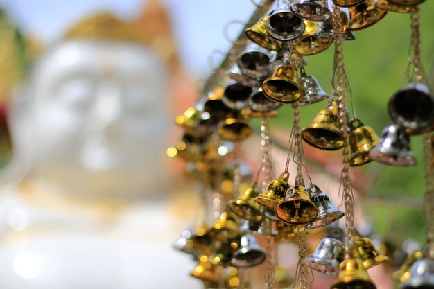 Foto close-up van kleine klokken die aan het standbeeld van boeddha hangen