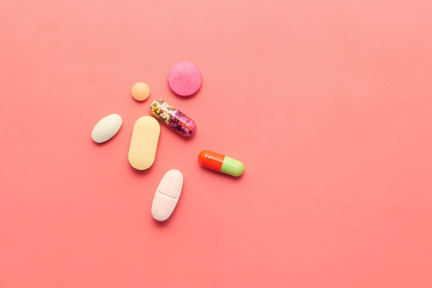 Close up van kleurrijke pillen en capsule op roze achtergrond.