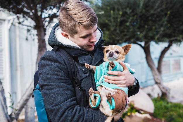 Close-up van knappe jonge man met een schattige chihuahua hond buiten.