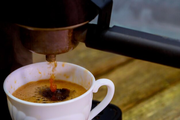 Foto close-up van koffie die in een beker op tafel wordt gegoten
