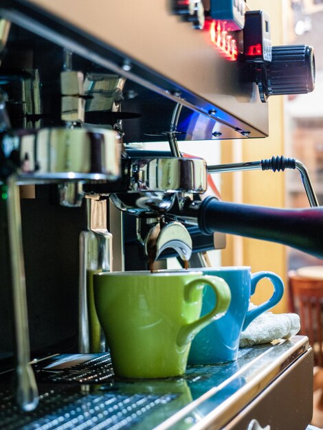 Foto close-up van koffie die in kopjes op machines wordt gegoten