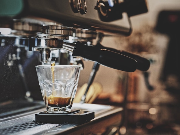 Close-up van koffie die uit de espresso-machine in een kopje wordt gegoten