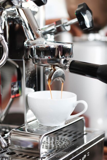 Close-up van koffie die uit de espresso-machine wordt gegoten in een kopje in een café