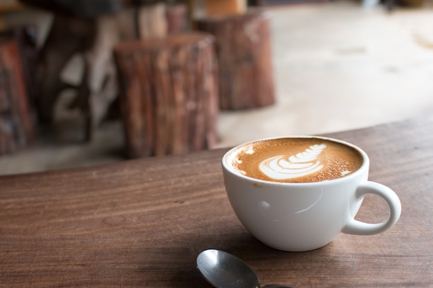 Close-up van kopje hete latte kunst koffie op houten tafel