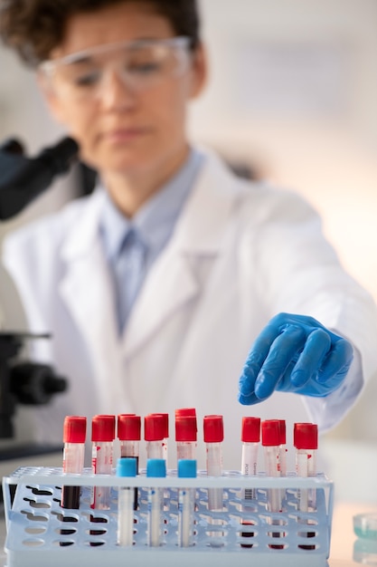 Close-up van laboratoriummedewerker in blauwe handschoenen die bloedmonsters in rek sorteren tijdens het maken van tests