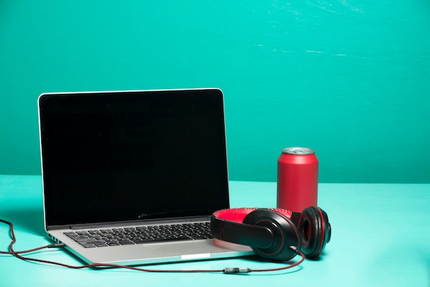 Foto close-up van laptop en koptelefoon tegen een turquoise achtergrond