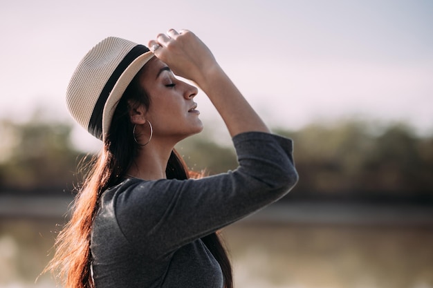 Close up van Latijnse brunette vrouw met hoed ontspannen op een dok bij de rivier Concept van ontkoppeling in de natuur