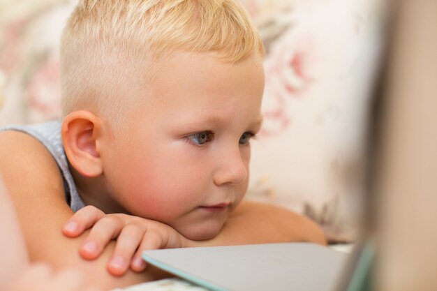 Foto close-up van little boy met behulp van tablet op sofa