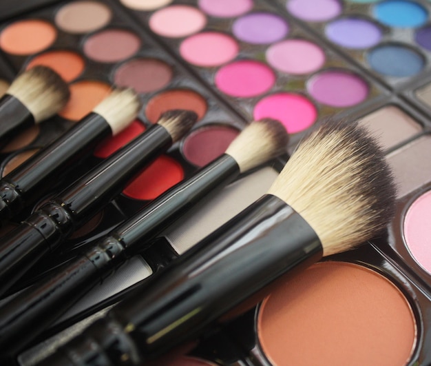 Close-up van make-up kwasten op kleurrijke oogschaduw palette
