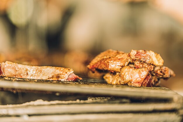 Close up van malse stukjes vlees koken in de grill van een restaurant.